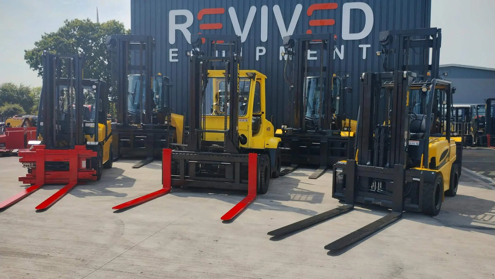 used forklift trucks in front of revived equipment signage